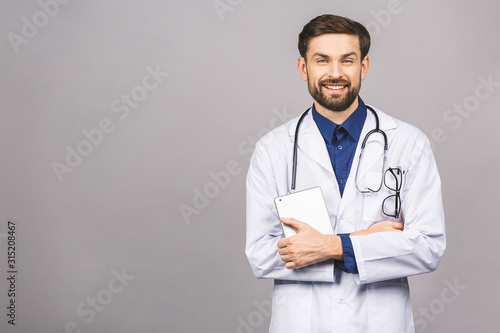 Smiling doctor using a tablet computer isolated on a grey background.