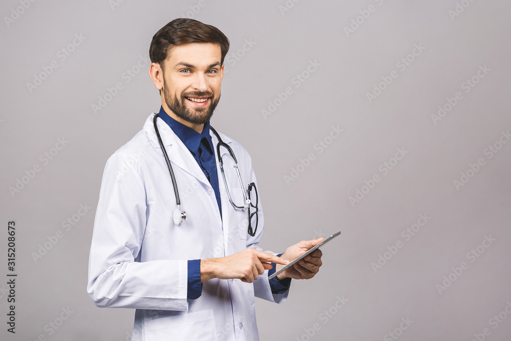 Smiling doctor using a tablet computer isolated on a grey background. Smiling doctor using a tablet computer isolated on a grey background.