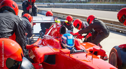 Pit crew replacing tires on formula one race car in pit lane photo