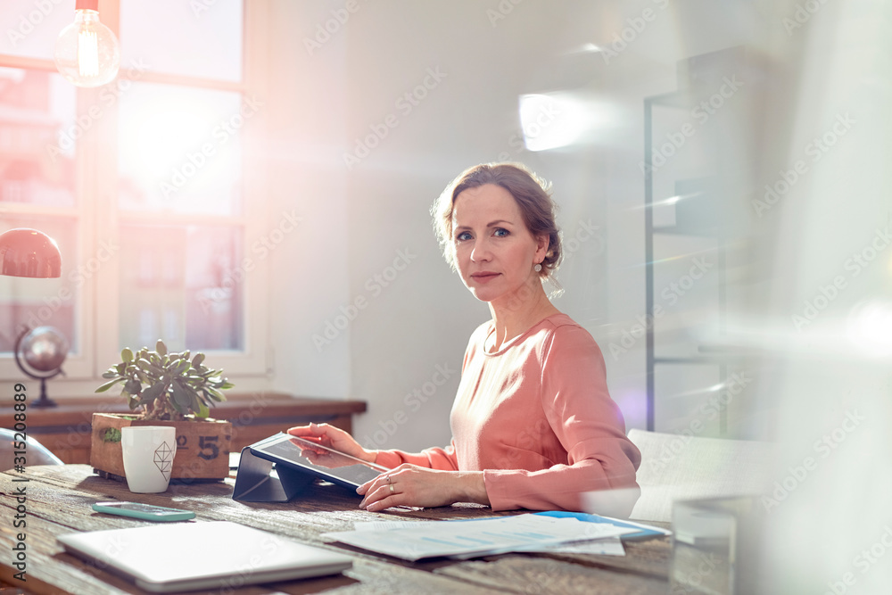 Portrait confident businesswoman using digital tablet at desk in office Portrait confident businesswoman using digital tablet at desk in office