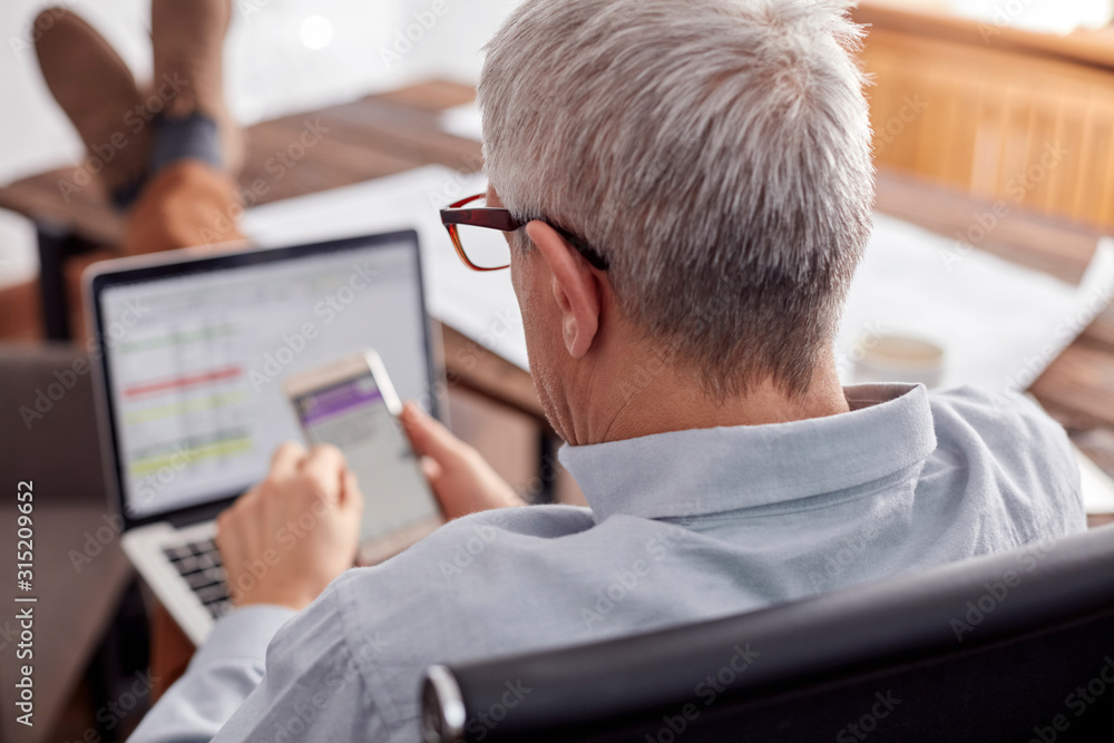Businessman working, using cell phone and laptop in office Businessman working, using cell phone and laptop in office