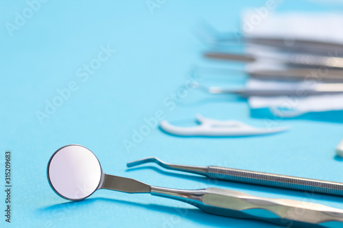 Set of Dentist s medical equipment tools. Stainless steel dental equipment on blue background with copy space.