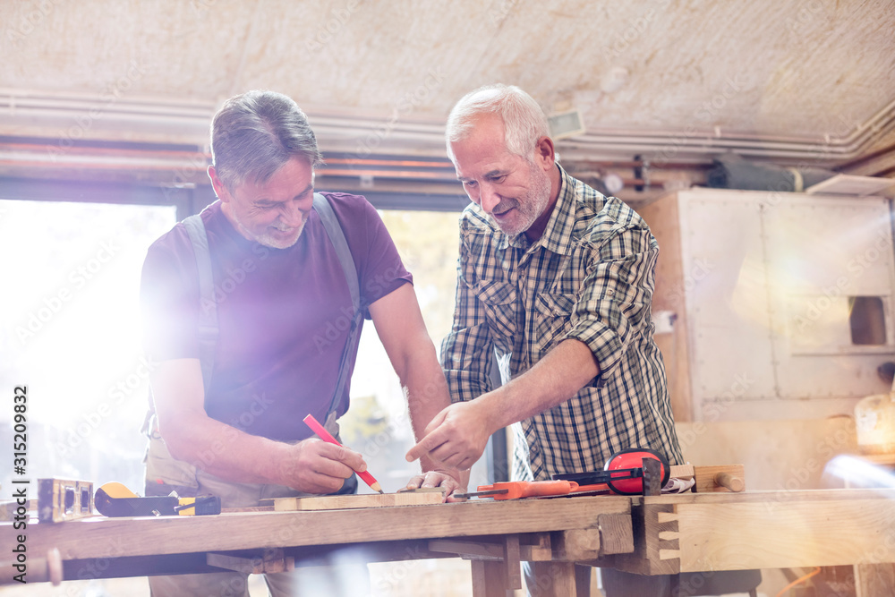 Male carpenters marking and measuring wood in workshop Male carpenters marking and measuring wood in workshop