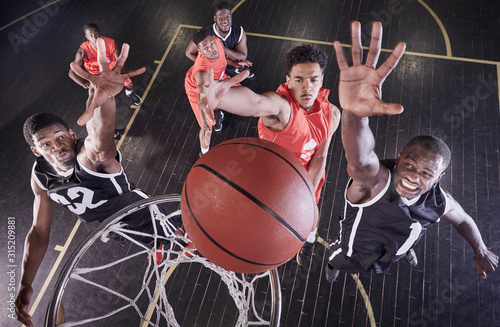Overhead view young male basketball players jumping to rebound basketball at net on basketball court
