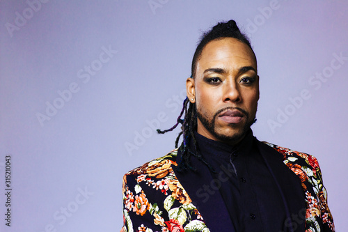 Studio portrait of a man wearing a flower patterned suit and dreadlocks photo