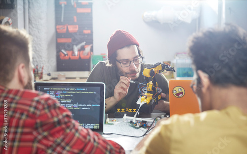 Computer programmers programming robotics in workshop