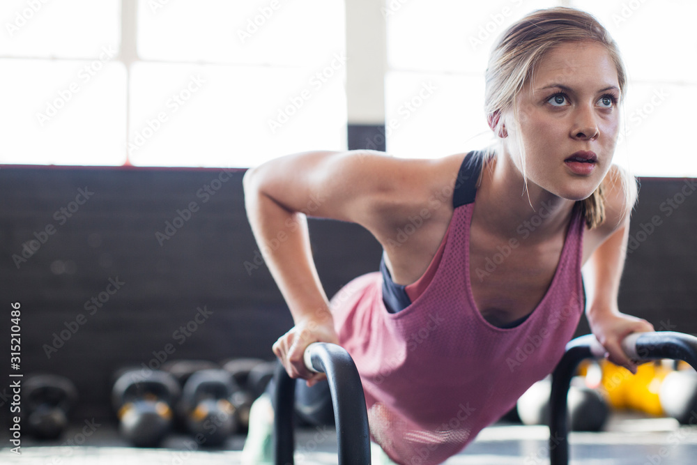 Portrait determined, focused young woman doing push-ups equipment in gym Portrait determined, focused young woman doing push-ups equipment in gym
