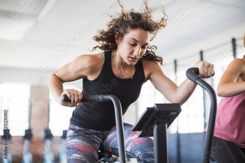 Determined young woman riding elliptical bike in gym photo