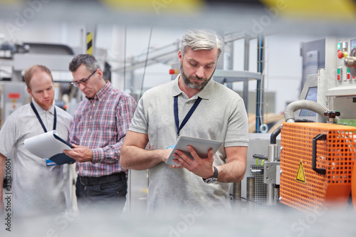 Male supervisor using digital tablet in fiber optics factory photo