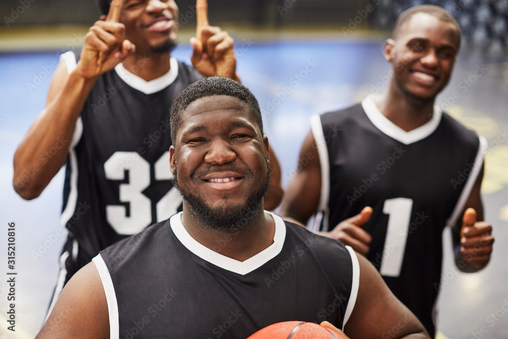 Portrait smiling, confident young male basketball player team in black jerseys gesturing, celebrating victory Portrait smiling, confident young male basketball player team in black jerseys gesturing, celebrating victory