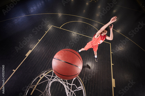 Young male basketball player shooting the ball on court in gymnasium