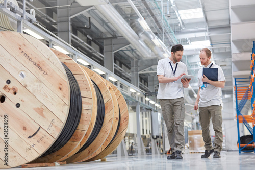 Male supervisor worker with clipboard walking in fiber optics factory