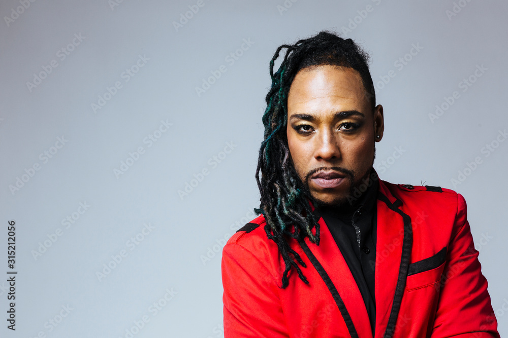 Fototapeta premium Closeup studio portrait of a man wearing a red jacket suit and dreadlocks