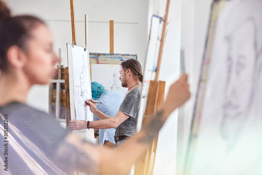 Artists sketching at easels in art class studio Artists sketching at easels in art class studio