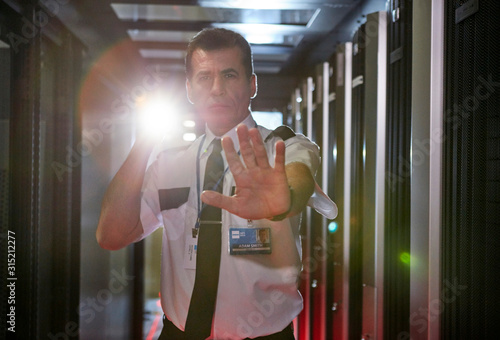 Portrait male security guard flashlight gesturing stop in server room photo