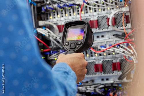 IT technician using diagnostic thermal imagining camera equipment in server room