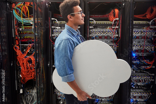 Male IT technician carrying cloud in server room, cloud computing