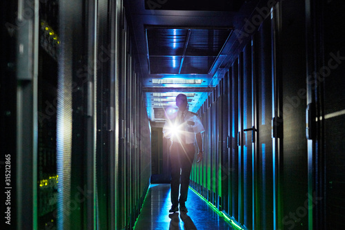 Male security guard with flashlight walking in dark server room