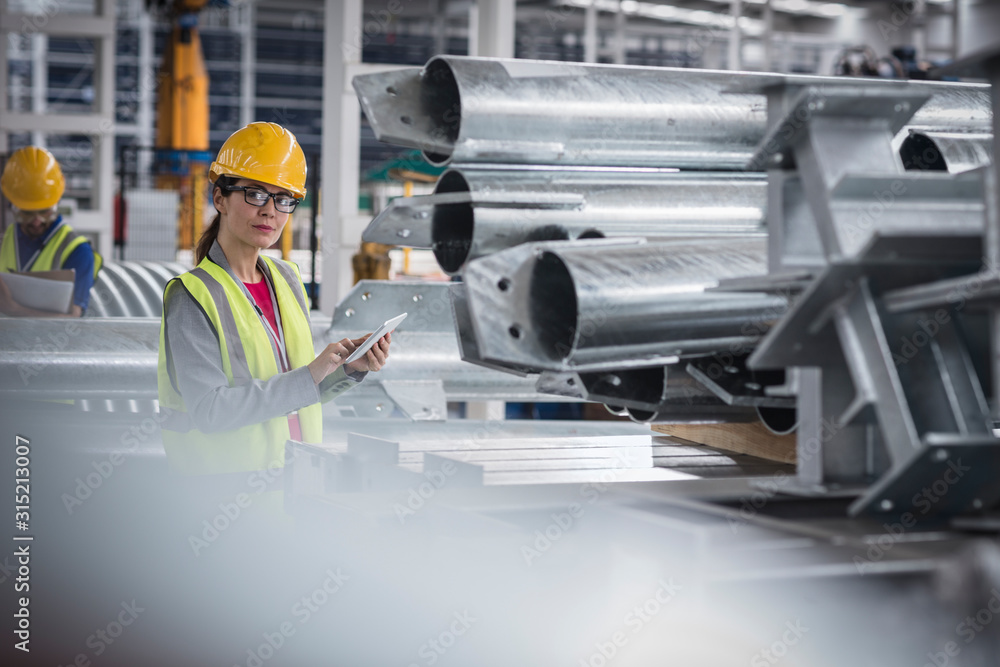 Portrait confident female worker with digital tablet in steel factory Portrait confident female worker with digital tablet in steel factory