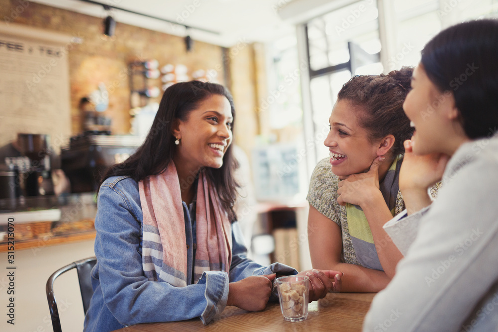 Smiling women friends talking at cafe table Smiling women friends talking at cafe table