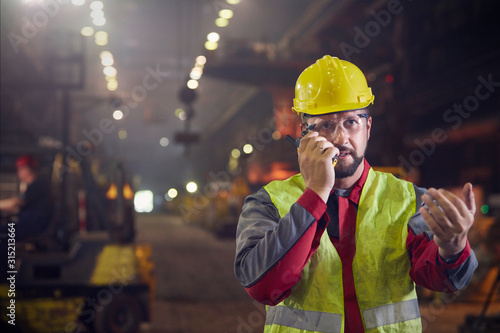 Steelworker talking, using walkie-talkie in steel mill photo