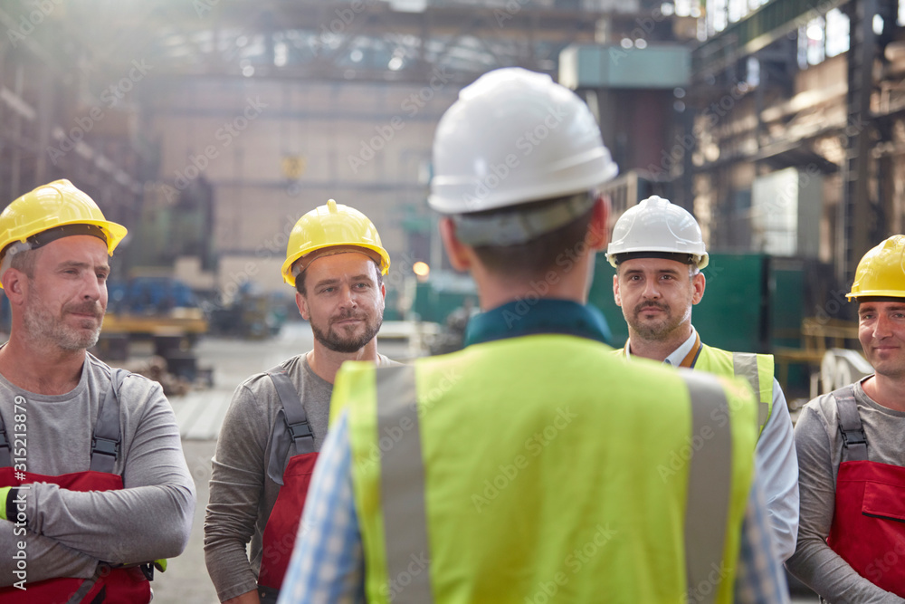 Male foreman talking, meeting with workers in factory Male foreman talking, meeting with workers in factory