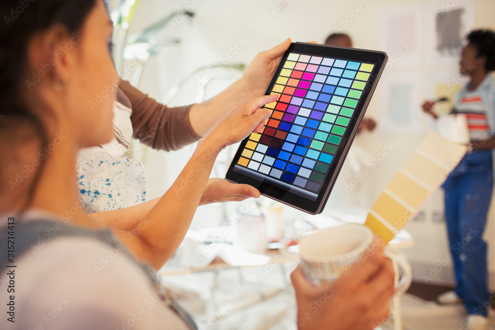 Young woman drinking coffee viewing digital paint swatches on digital tablet Young woman drinking coffee viewing digital paint swatches on digital tablet