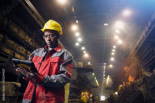 Steelworker using digital tablet in steel mill