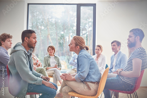 Group watching man woman talking face to face in group therapy session photo