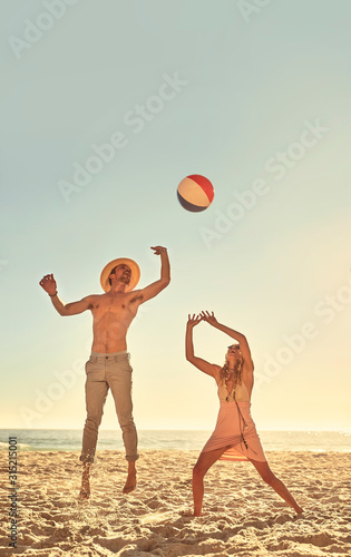 Young couple playing with beach ball on sunny summer beach