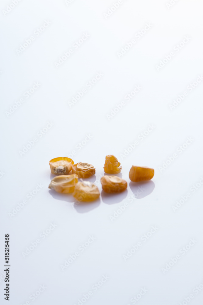 Dry corn grain seeds. White isolated background, cutout. Dry corn grain seeds. White isolated background, cutout.