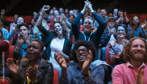 Excited audience clapping in dark room