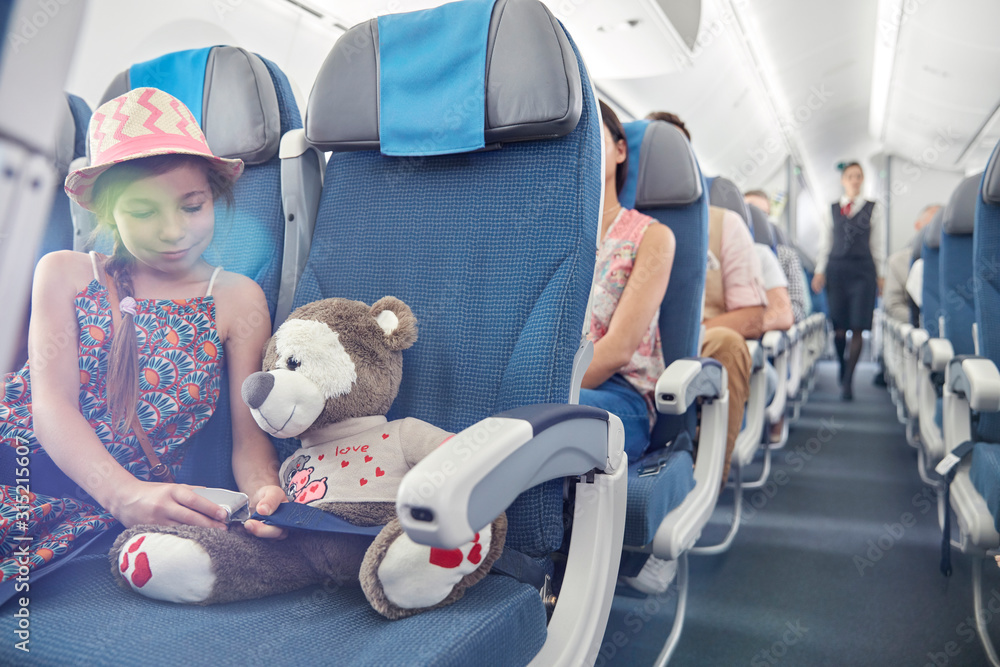 © Caiaimage/Agnieszka Olek/Caia Image - Girl fastening seat belt on stuffed animal on airplane