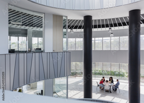 Business people meeting at table in architectural, modern office atrium