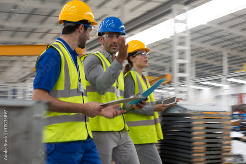 Supervisors with clipboard and digital tablet walking in warehouse photo