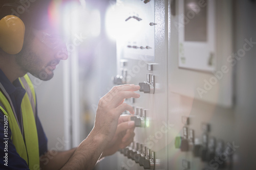 Male worker operating machinery at control panel in factory