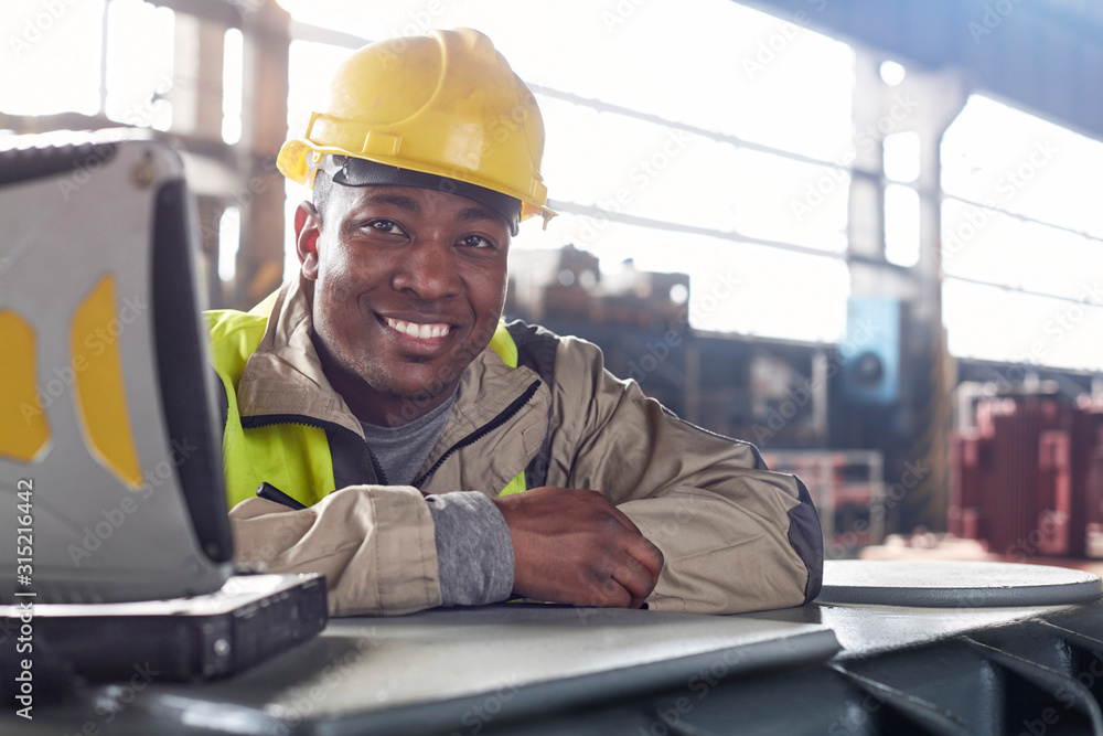 Portrait smiling, confident steelworker at laptop in steel mill Portrait smiling, confident steelworker at laptop in steel mill