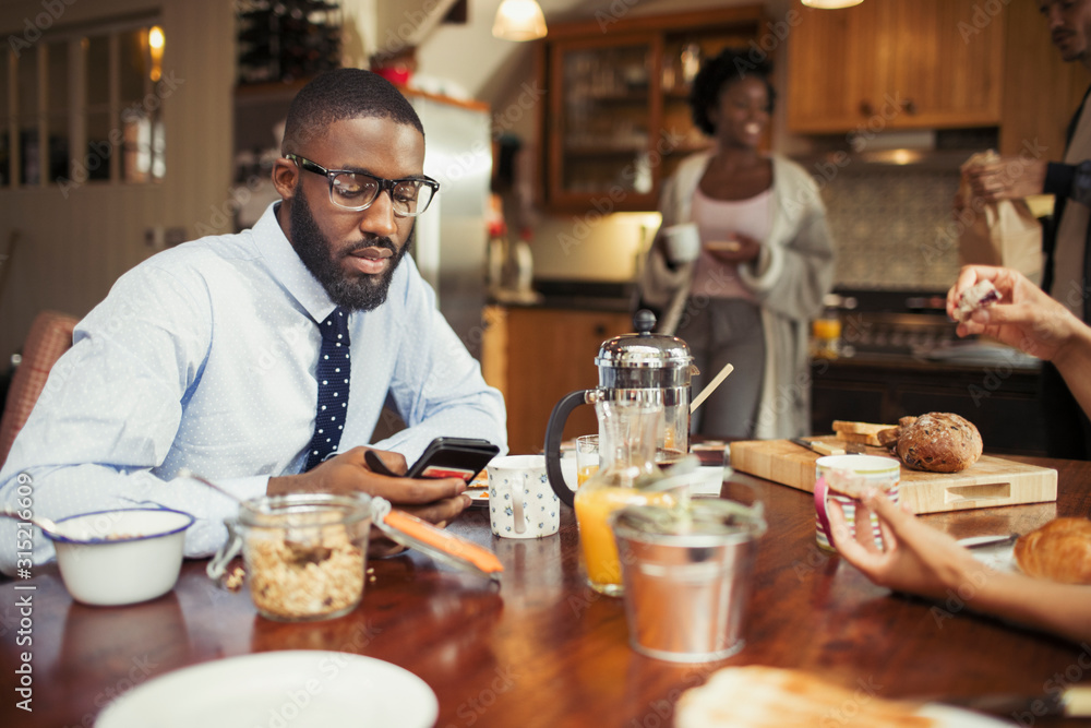 Businessman texting with smart phone at breakfast table Businessman texting with smart phone at breakfast table
