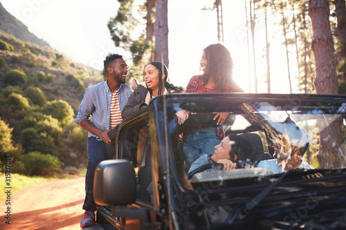 Young friends enjoying road trip in jeep in woods photo