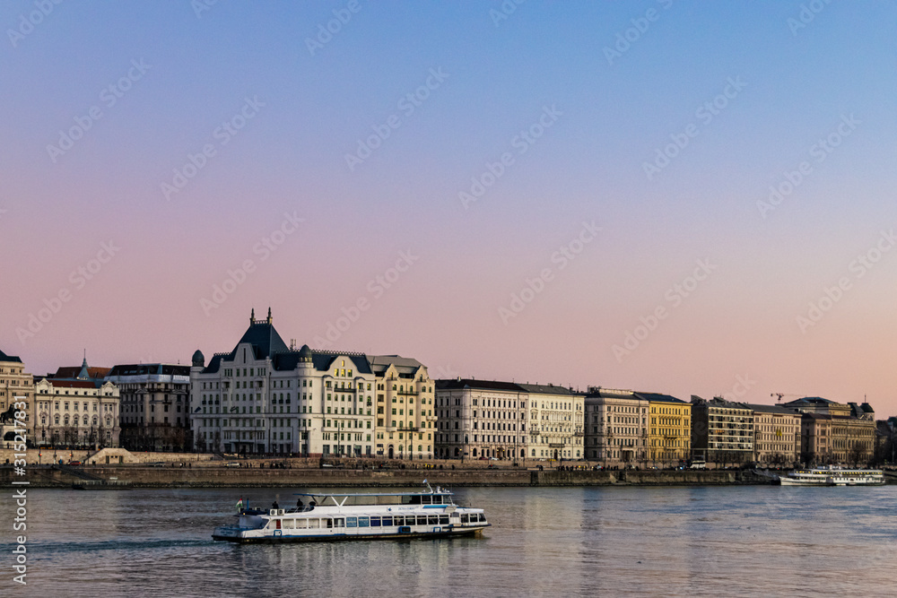 Tourist cruise boat traveling up the Danube river after sunset.