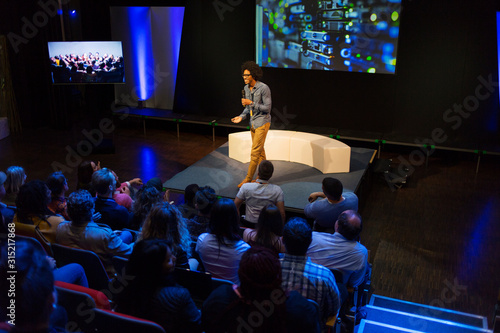 Audience watching male speaker on stage