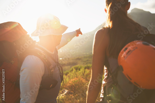 Rock climbers pointing to sunny mountain