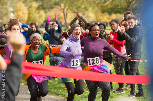 Enthusiastic female runners in tutus nearing finish line at charity run photo