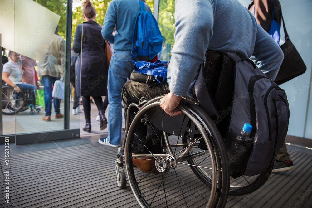 Man in wheelchair leaving office Man in wheelchair leaving office