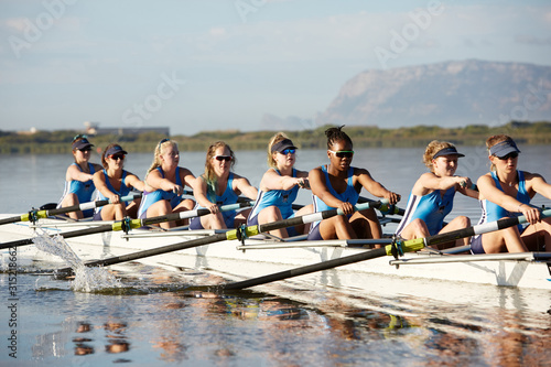 Female rowers rowing scull on sunny lake photo