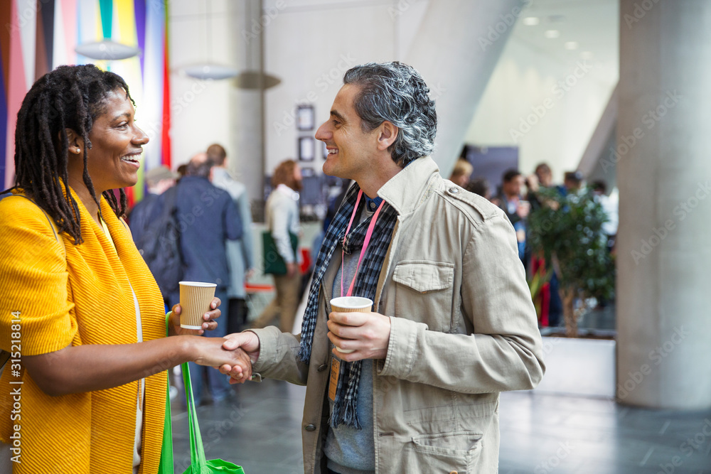 © Sam Edwards/Caia Image - Businessman and businesswoman networking, handshaking at conference