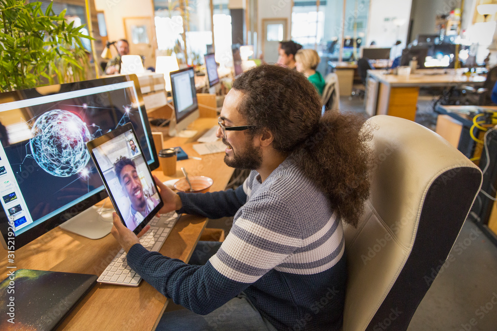 Creative designer video chatting colleague on digital tablet in office Creative designer video chatting colleague on digital tablet in office