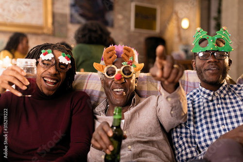 Portrait playful grandfather grandsons wearing Christmas costume goggles photo