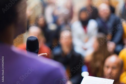 Businessman with microphone speaking to conference audience photo