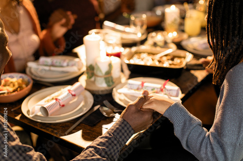 Family holding hands, praying at Christmas dinner photo